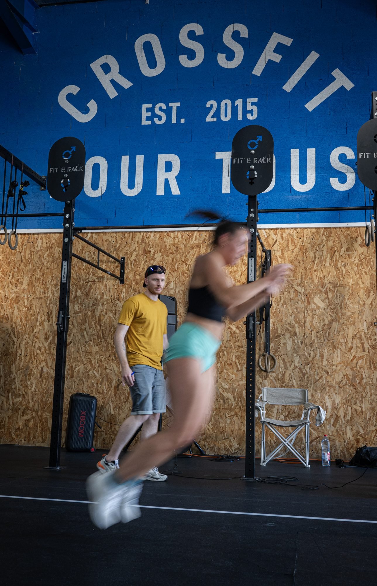 Athlète en plein saut devant le mur CrossFit pour tous